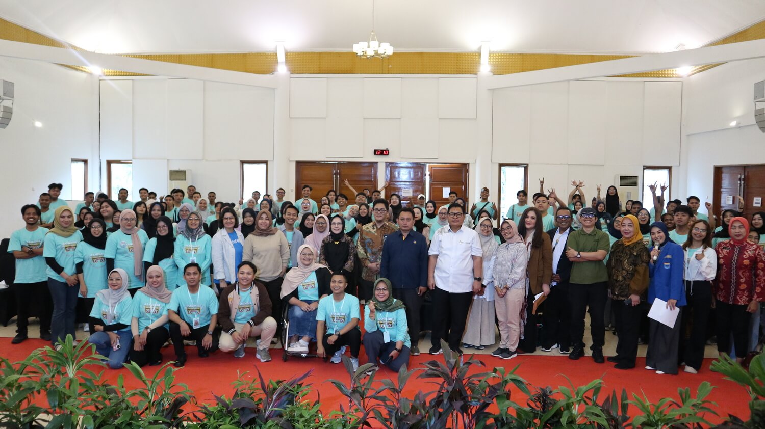 A large group of Youth Jamboree 2025 participants in turquoise t-shirts posing with Bappenas and Australian Embassy representatives.