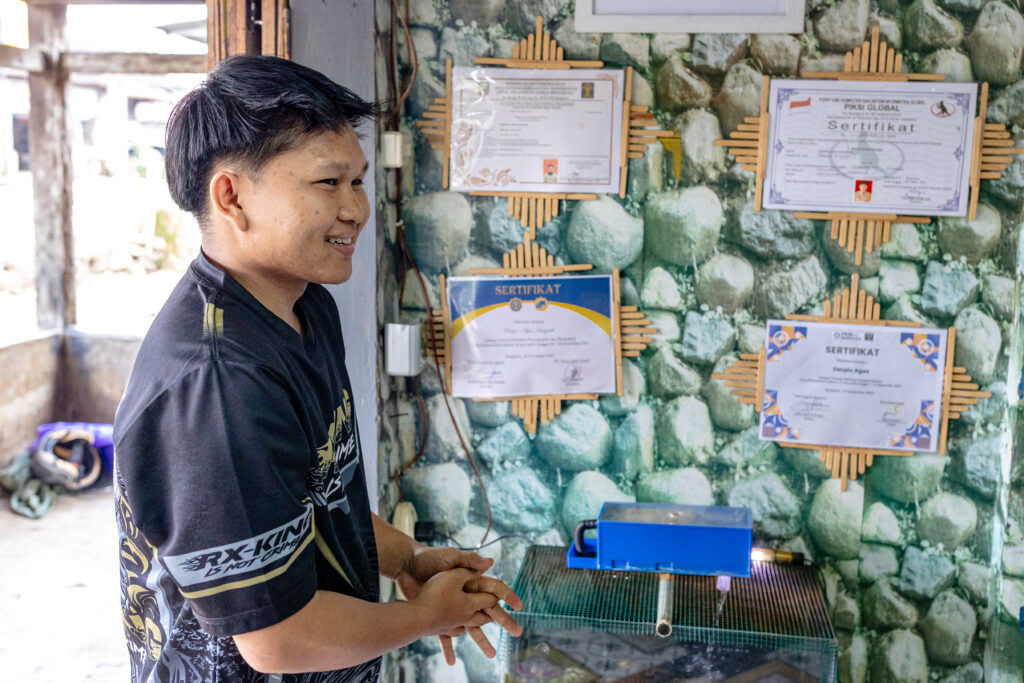 A former juvenile detainee poses in front of several skills training certificates he has earned.
