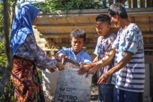 empat orang dengan disabilitas, bersama-sama menyiapkan pakan di area kandang kambing.