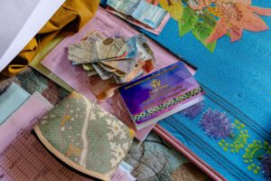 A Credit Union savings and loan book alongside cash and financial records placed on a patterned pouch.